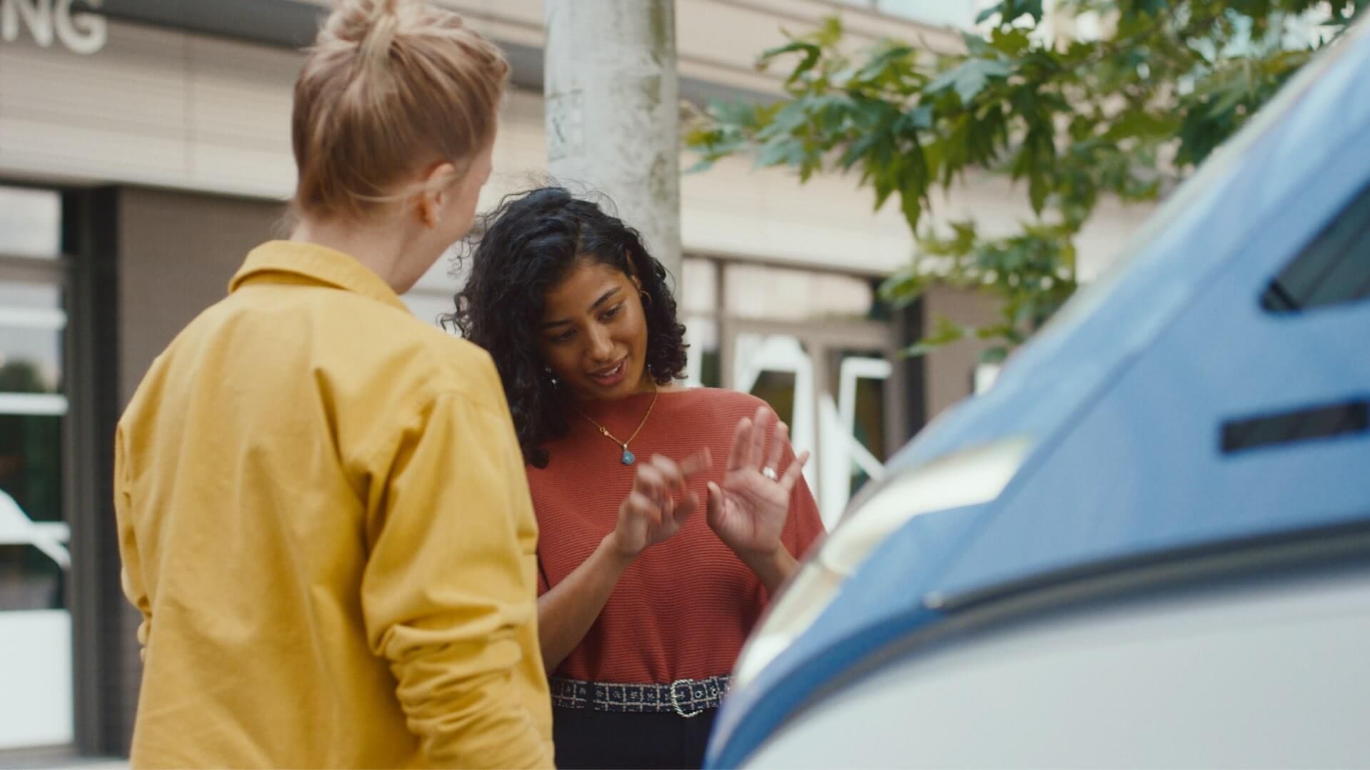 Zwei Frauen unterhalten sich neben VW ID. Buzz