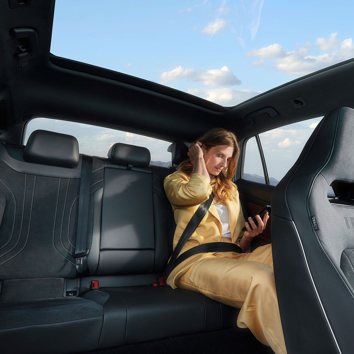 Frau sitzt auf der Rückbank des VW ID.5 und blickt auf ihr Smartphone