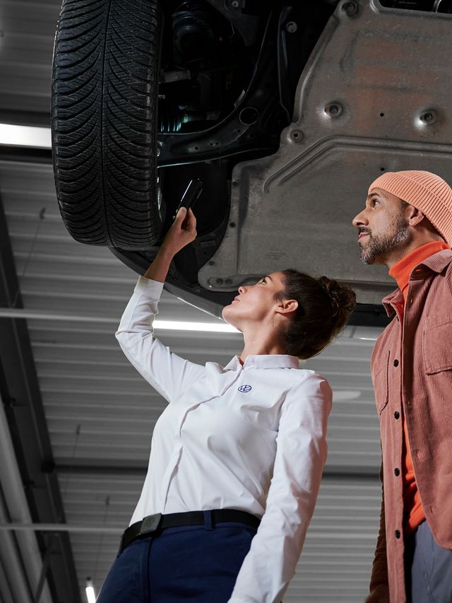 Eine Volkswagen Technikerin bespricht die Reparatur mit einem Kunden