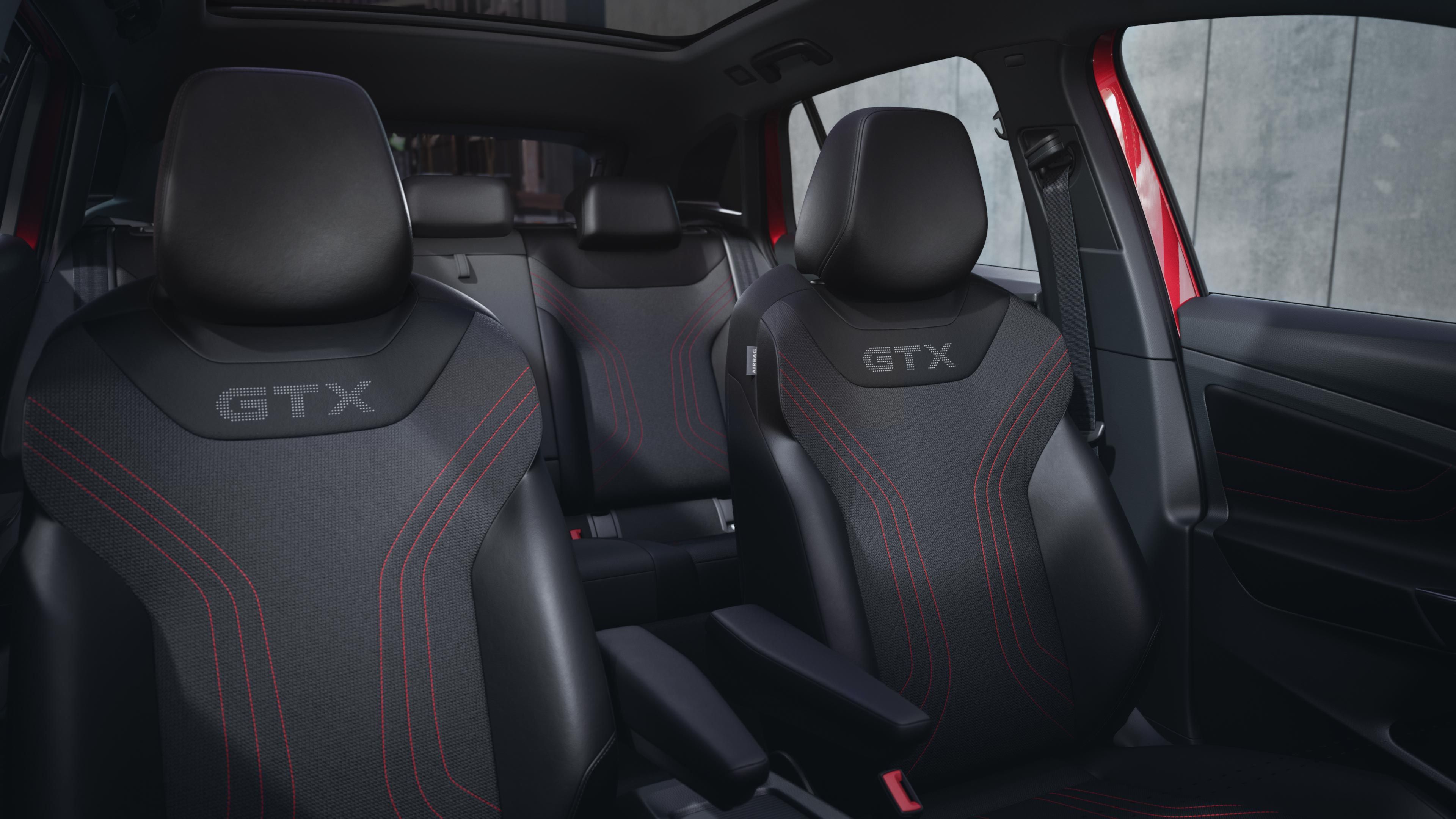 Innenansicht des VW ID.4 GTX von der Mittelkonsole aus. Zu sehen sind die Vordersitze mit GTX-Logo und roten Details sowie ein Teil der Rückbank.
