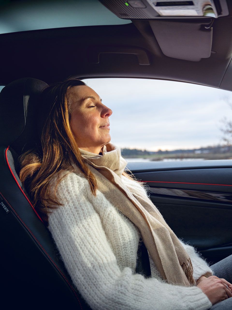 Eine Frau sitzt im geparkten VW ID.7 Tourer GTX und schließt die Augen