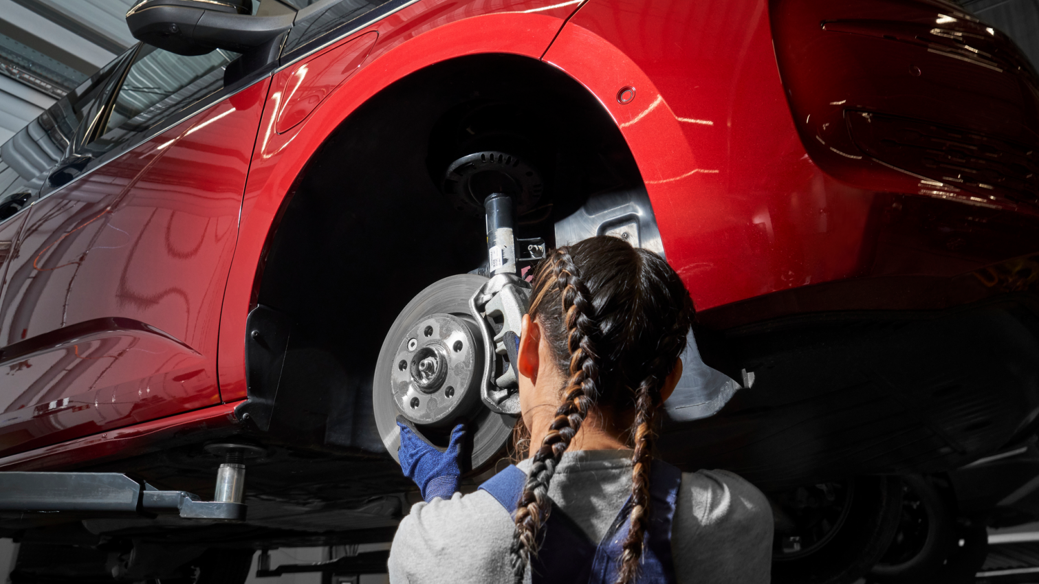 Eine VW Mechanikerin wechselt die Bremsscheiben bei einem VW Nutzfahrzeug