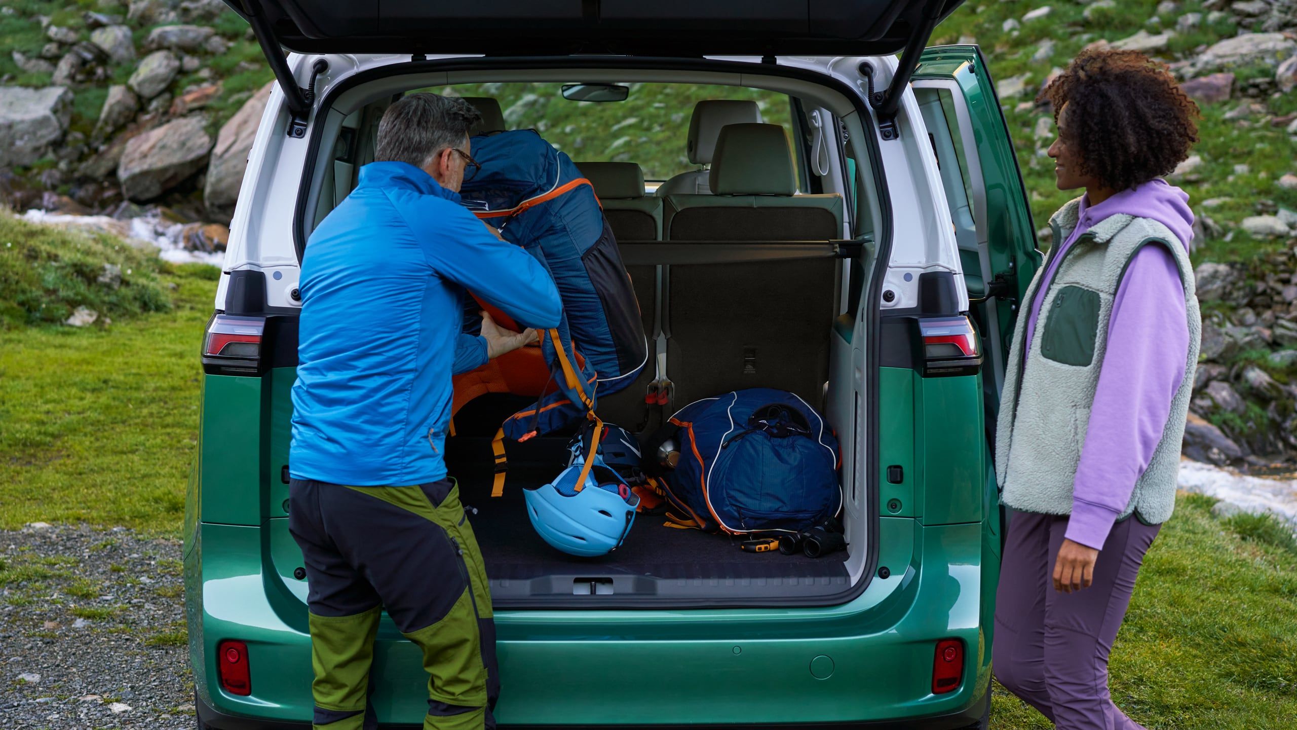 Offene Heckklappe des VW ID. Buzz und zwei Personen entnehmen Kletterausrüstung