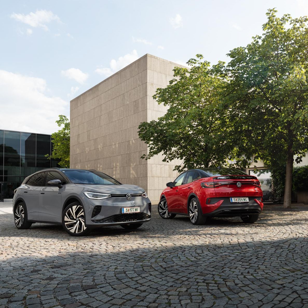 Ein grauer VW ID.4 und ein roter VW ID.5 geparkt vor Gebäude