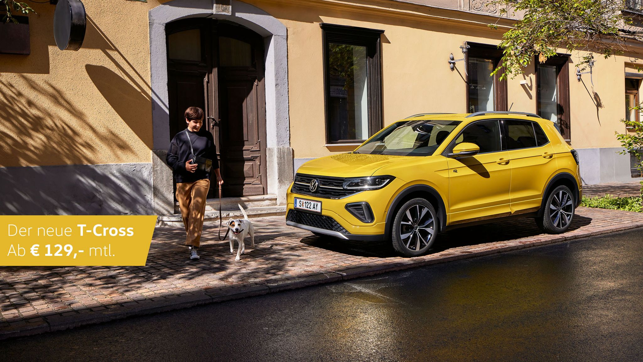 Ein gelber VW T-Cross steht geparkt am Straßenrand. Eine Frau läuft mit ihrem Hund vor dem Auto entlang. Mit auf dem Bild steht die monatliche Leasingrate. 